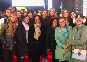 A group of people gather for a photo on red steps in the middle of Times Square.