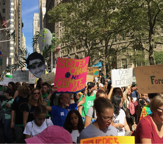 The city street is filled with people carrying signs during a Climate march.