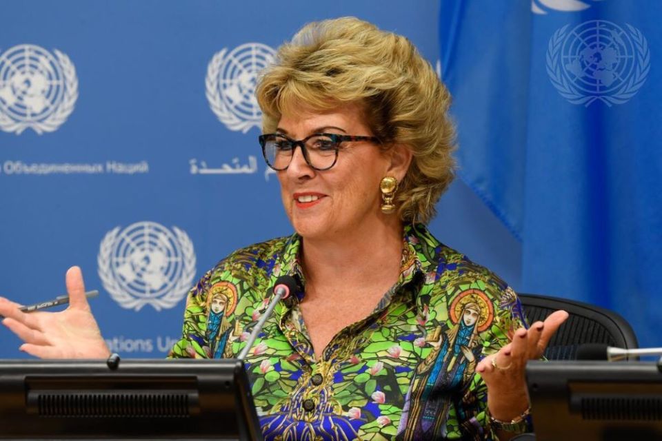 Woman with glasses sits in front of United Nations backdrop
