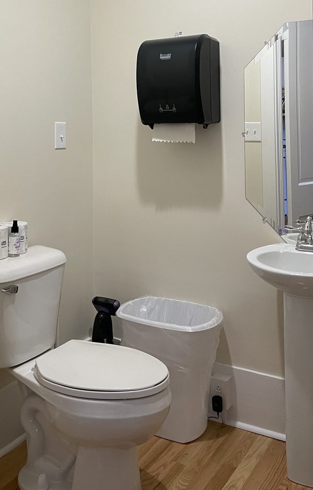 View of a small bathroom - toilet, sink, garbarge can and paper towel dispenser