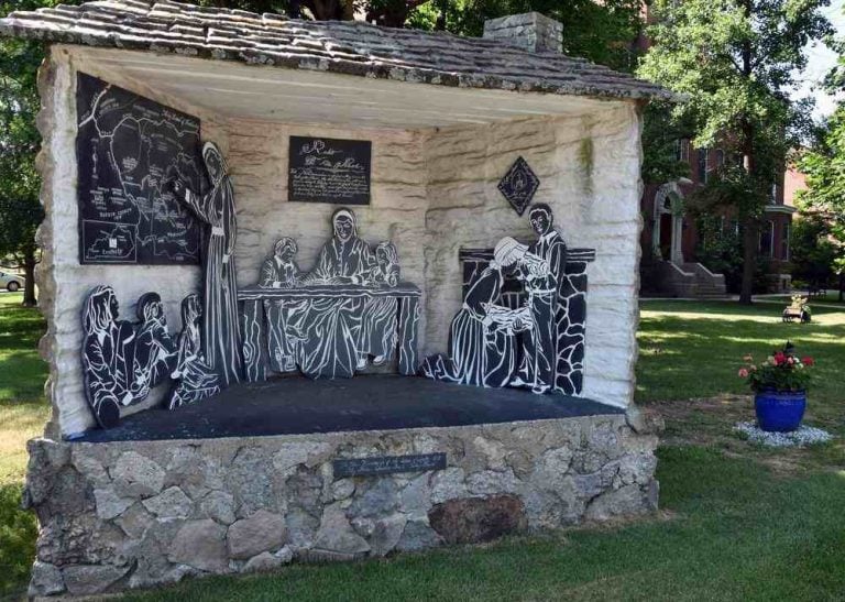 A triptych sculpture displays habited sisters teaching and serving children.