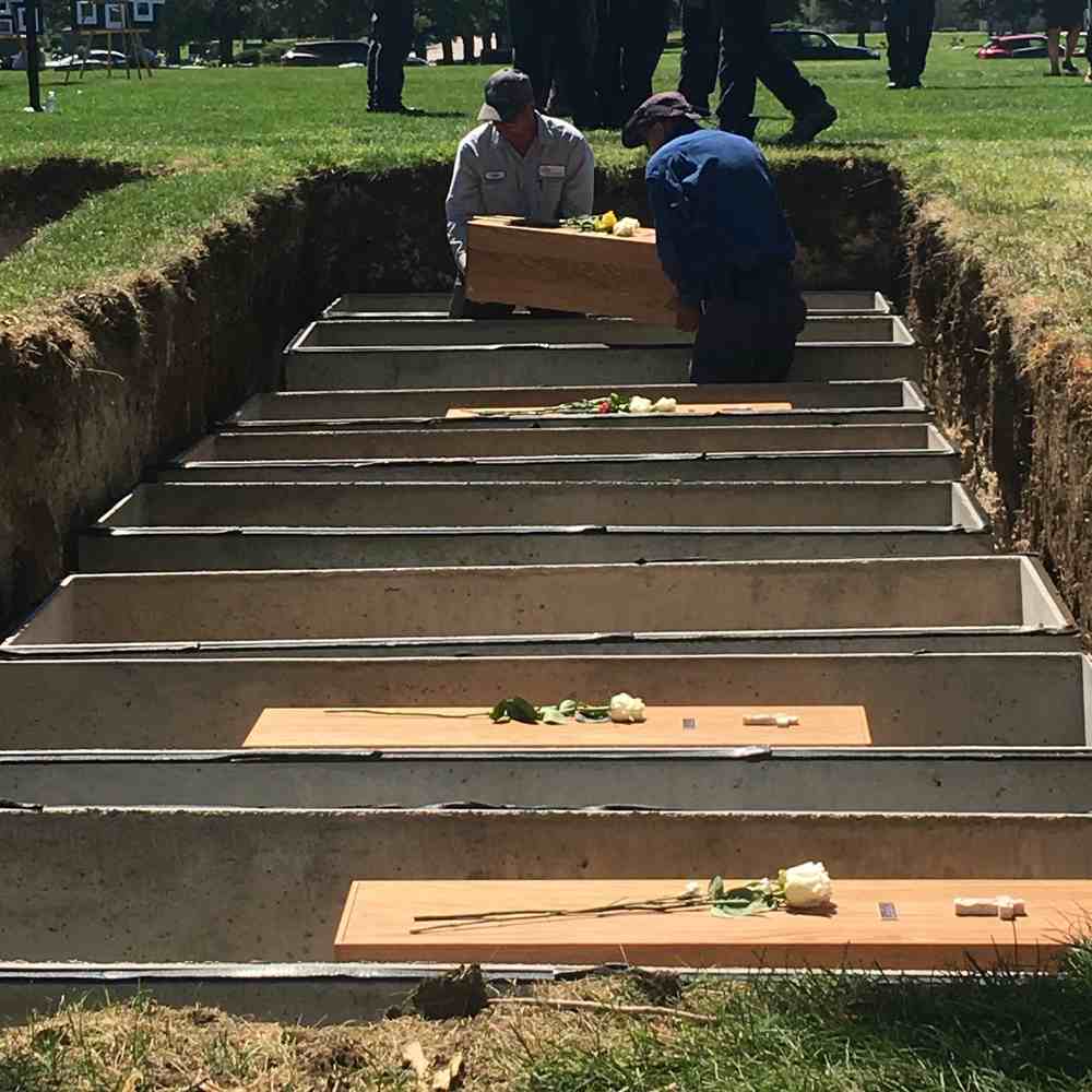 Wooden coffins are being carefully placed inside metal sarcophagi. 