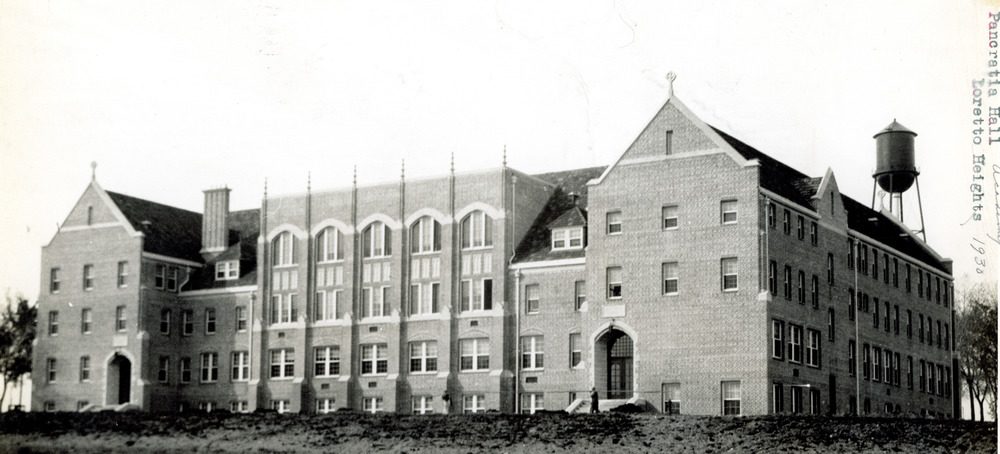 Historic photo of a four-storey brick building with a center hall and two wings