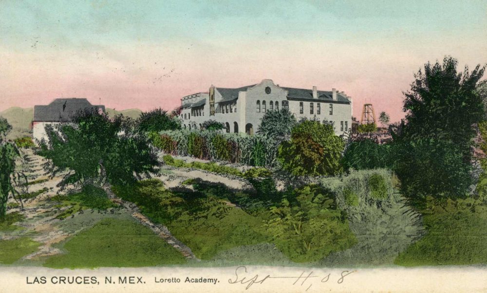Historic postcard showing a white, southwest-style building with low trees and shrubs surrounding in and in the foreground. Printed text on the bottom reads "Las Cruces, N. Mex. Loretto Academy" The date "Sept 11, [19]08" is handwritten.