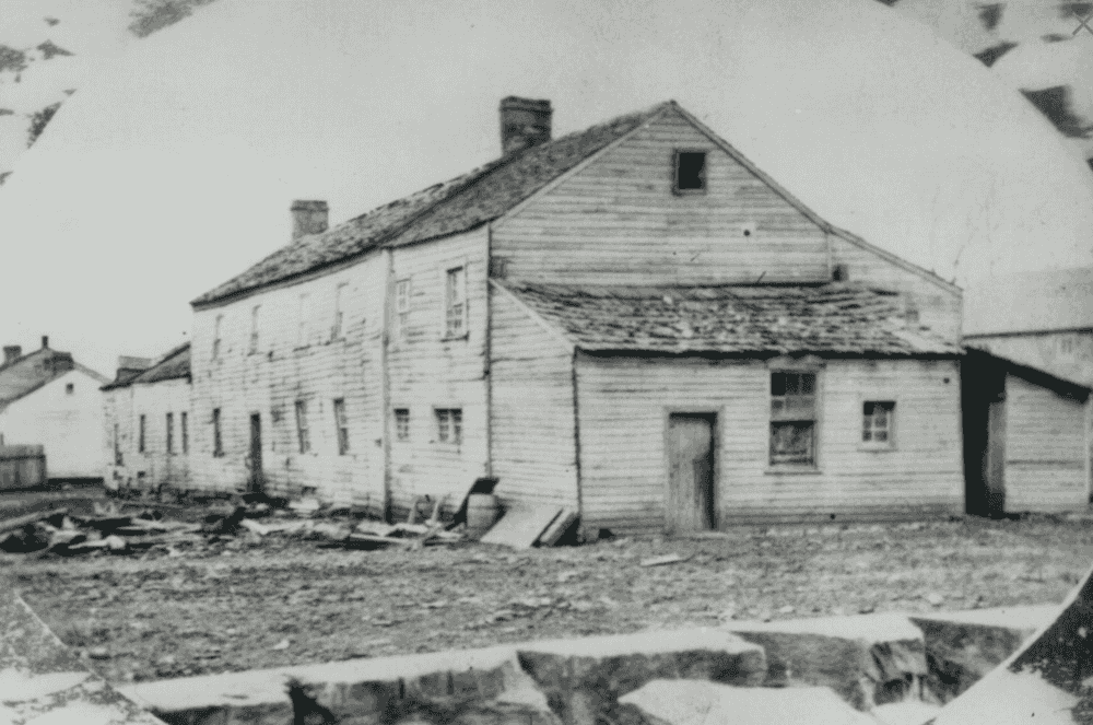 Black and white photo of a large white clapboard building.