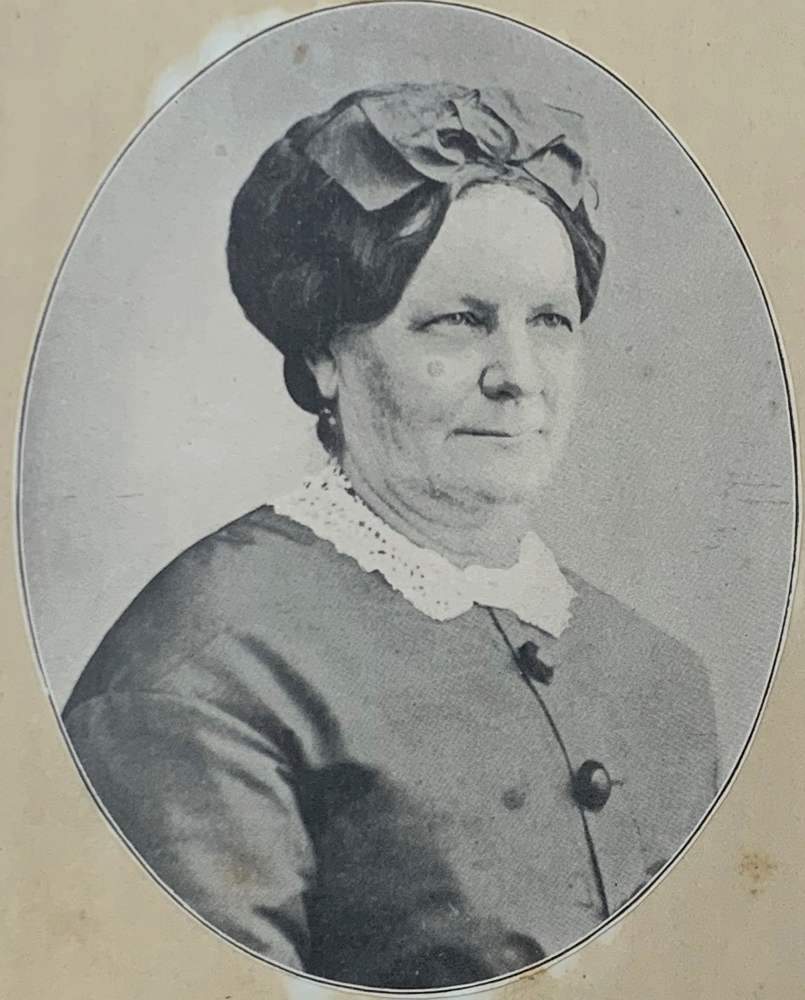 Mid-1800's Portrait of a woman in a buttoned-up dress with a lace collar. Her hair is pulled up with a wide ribbon. 