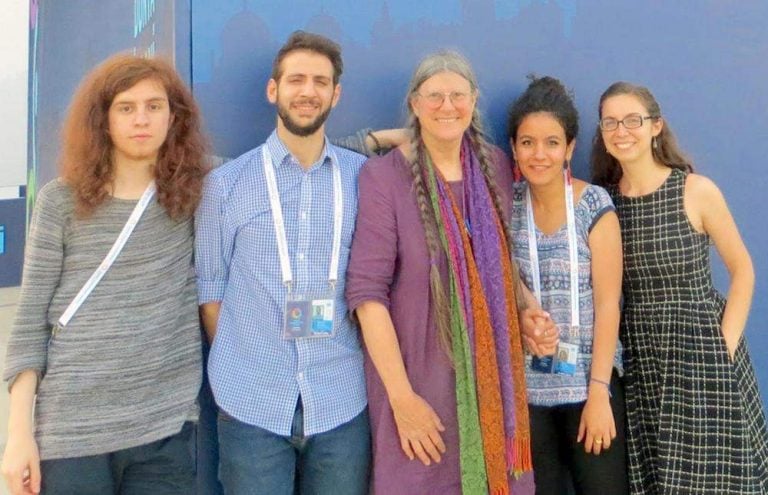 Five diverse individuals smiling together for a photo.
