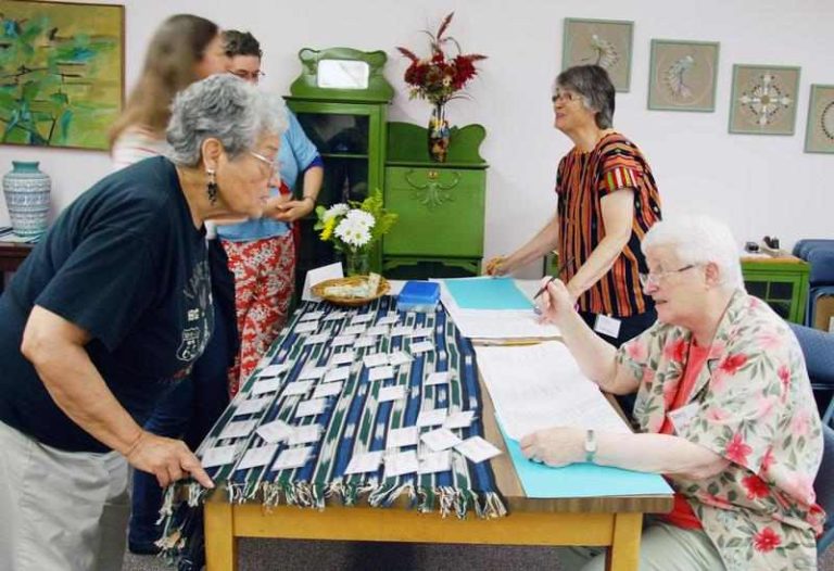 Women working and conversing together across a table for registration.