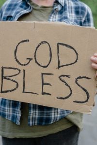 a man holding a god bless sign written on a cardboard
