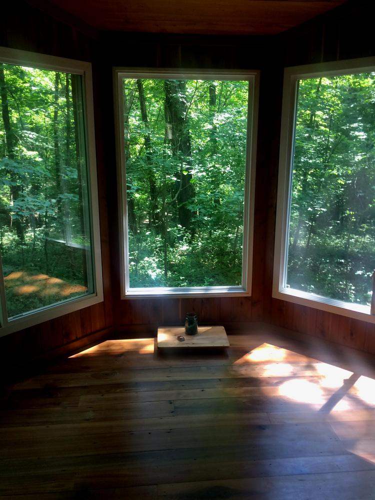 Light streams in three large bay window that look out into the woods.