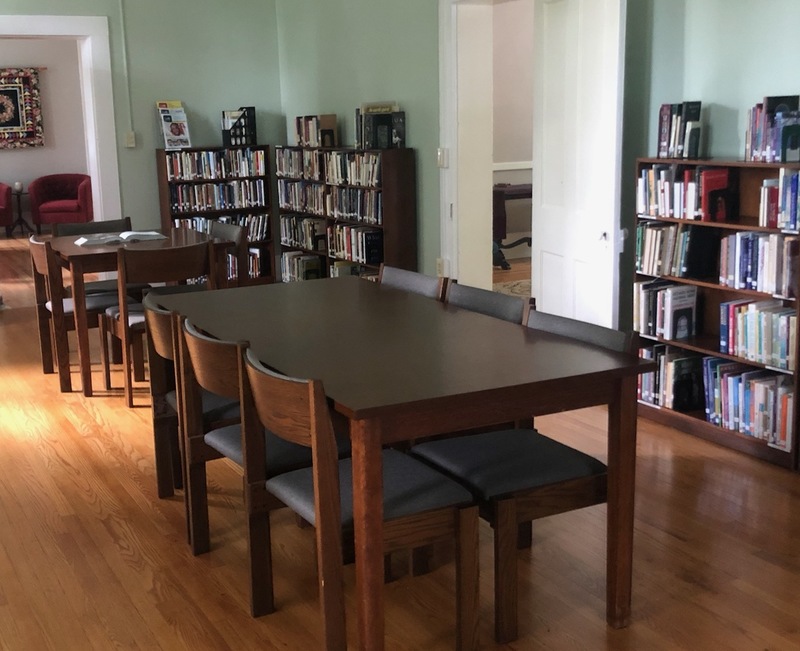Two tables with chairs in a room lined with bookcases.