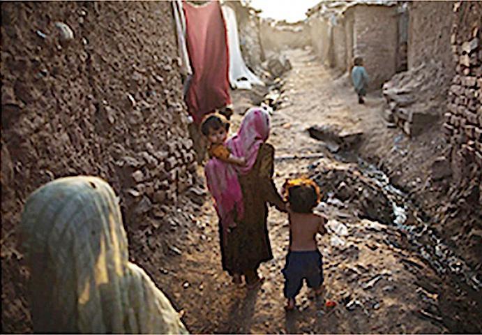 Pakistani women walking through an area with open sewers.