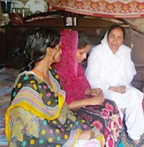 Three Pakistani women sitting together in traditional clothing conversing.