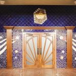 A grand theatre entrance with large wooden doors and blue mosaic detailed with shooting stars and planets.