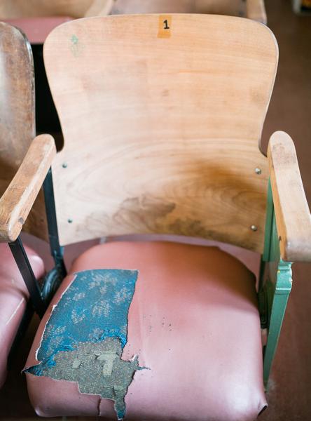 Battered and patched wooden auditorium chair.