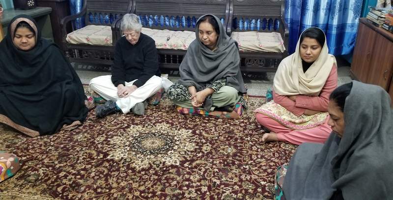 Five women sit on the floor in prayer.