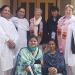 Seven women gather for a photo. Five are in white tunics and pants; two are in traditional Pakistani dress.