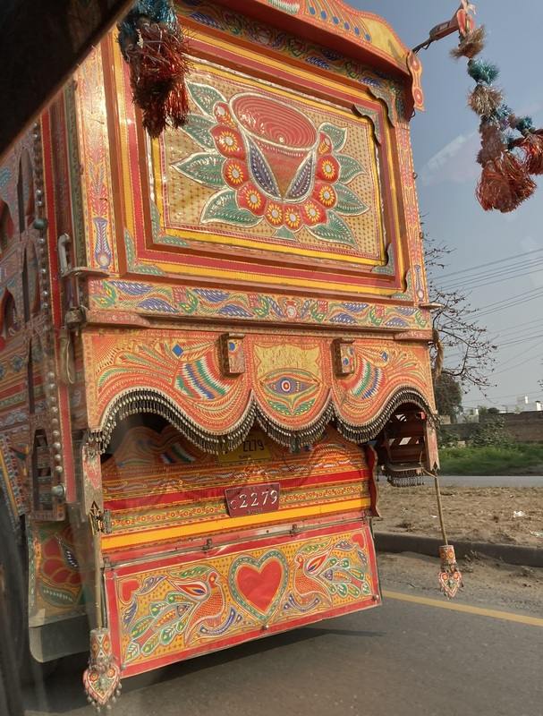 Large orange and red truck ornately decorated with hearts, birds and flowers.