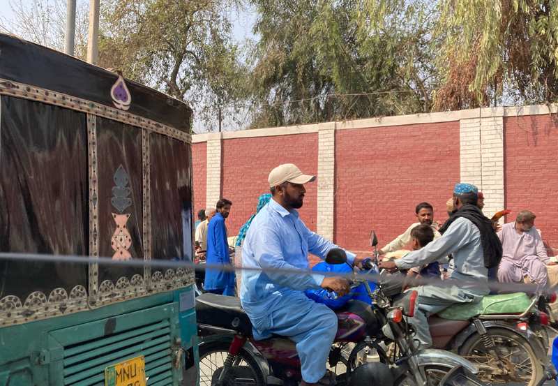 A bus and men on motorcycles pass on a street