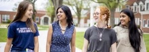four diverse women conversing on a walk outside smiling.