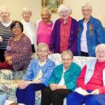 A wide variety of individuals gathered together at an indoor community event smiling for a picture.