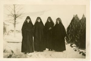 Four Sisters of Loretto stand side by side in the snow in heart shaped habits.