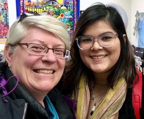 Two women, both wearing glasses, smiling for a selfie.