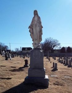 A blessed mother statue in a religious cemetery surrounded by 42 graves.