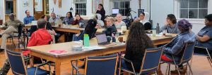An overview image of staff and board members sitting, conversing, and working indoors.