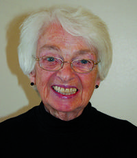 Short-haired woman wearing black turtleneck and glasses smiling for a headshot.