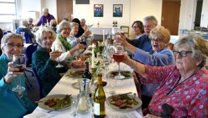 A diverse table make a toast and smile at the dining table inside.