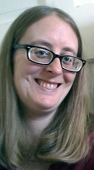 Woman with mid length hair and glasses smiles for a selfie.