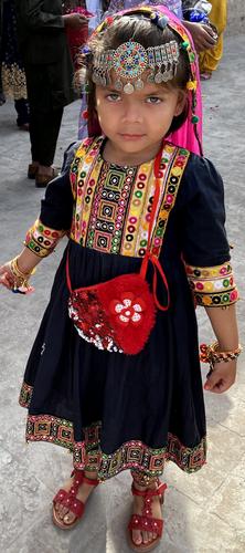 A young girl in traditional clothing garments and a head piece to welcome incoming guests.