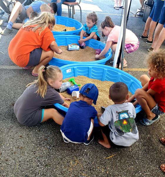 Children playing with grain filled kiddie pools in a parking lot.