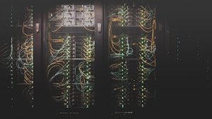 A dark photo of a wiring system behind mesh screen doors.