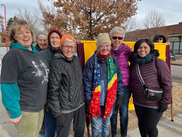 A group of people in winter coats smiling while attending a march.