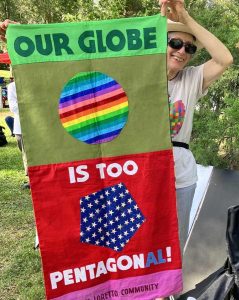Loretto Community member holds a banner made by Robert Strobridge CoL that reads "Our globe is too Pentagonal!"