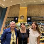 Three women smiling for a picture in the United Nations building.