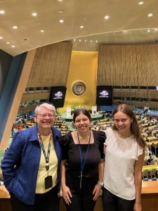 Three women smiling for a picture in the United Nations building.