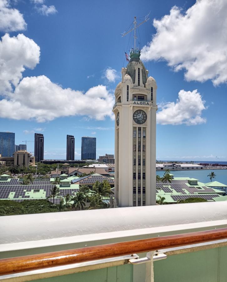 A photo taken from the deck of a boat of a city skyline in Hawai'i, with the "Aloha tower" in the foreground.