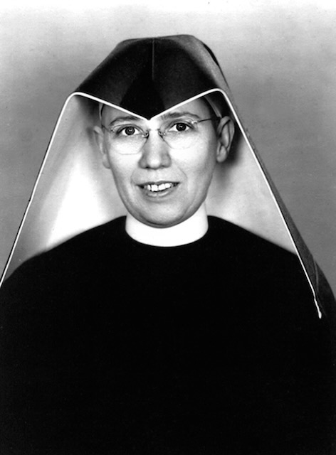 Black and white photo of a nun with round glasses in a habit.