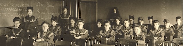 Sepia toned 1904 picture of students sitting in a classroom.