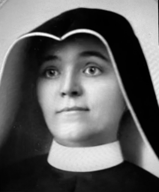 Black and white photo of a young nun in a traditional habit.