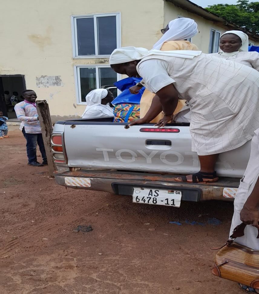 Several FST sisters in white habits pack up a silver toyota pickup truck with donated clothing.