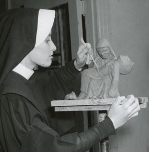 Archival photo of a habited nun sculpting the piéta.