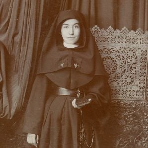 Archival formal photo of a young Sister Lucia Perea in habit holding her bible and posing.