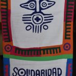 a colorful banner that features an indigenous symbol in the middle with the words "Solidaridad" and "The Loretto Community" underneath it.