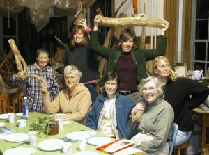 Seven women gather for a lighthearted photo at a dinner table in Jeanne Dueber's art studio.