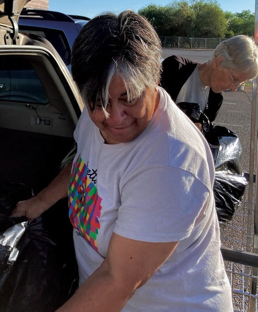 Two woman are shown unloading bags of laundry from a car.