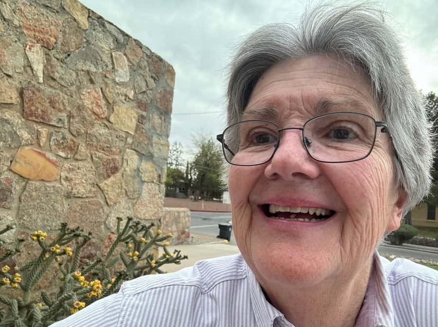 Jane German snaps a selfie with blooming cactus and a stone wall.